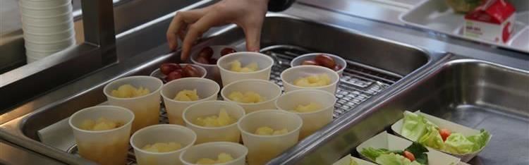 Student picking up fruit cups at cafe line. 