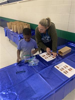 Mrs. Walendzik helping a student with a craft at family night