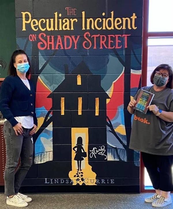 Author Lindsay Currie and Mrs. Walsh, ELA teacher pose with the mural of Lindsay's book.