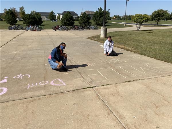 Students write messages on the sidewalk