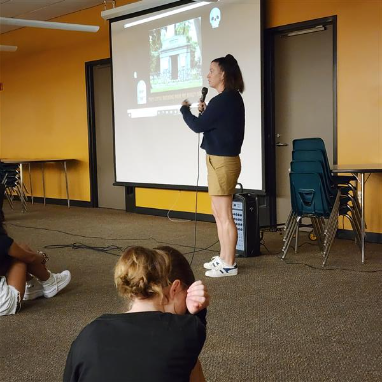 Author Lindsay Currie speaks to students in front of a slide presentation