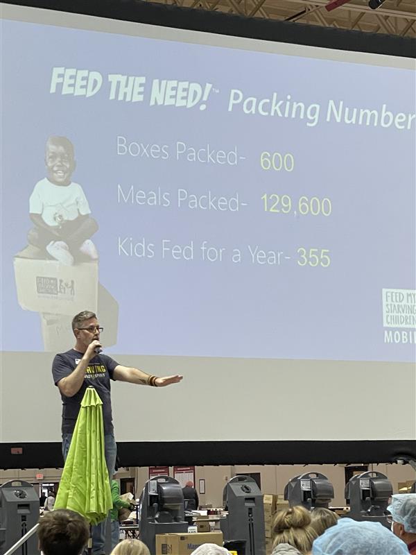 A speaker in front of a projector screen