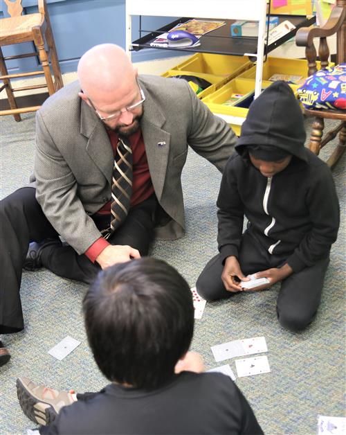 Dr. Sparlin watching 2 students play a game of war