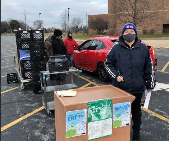 Food services staff outside helping people receive food at a car.